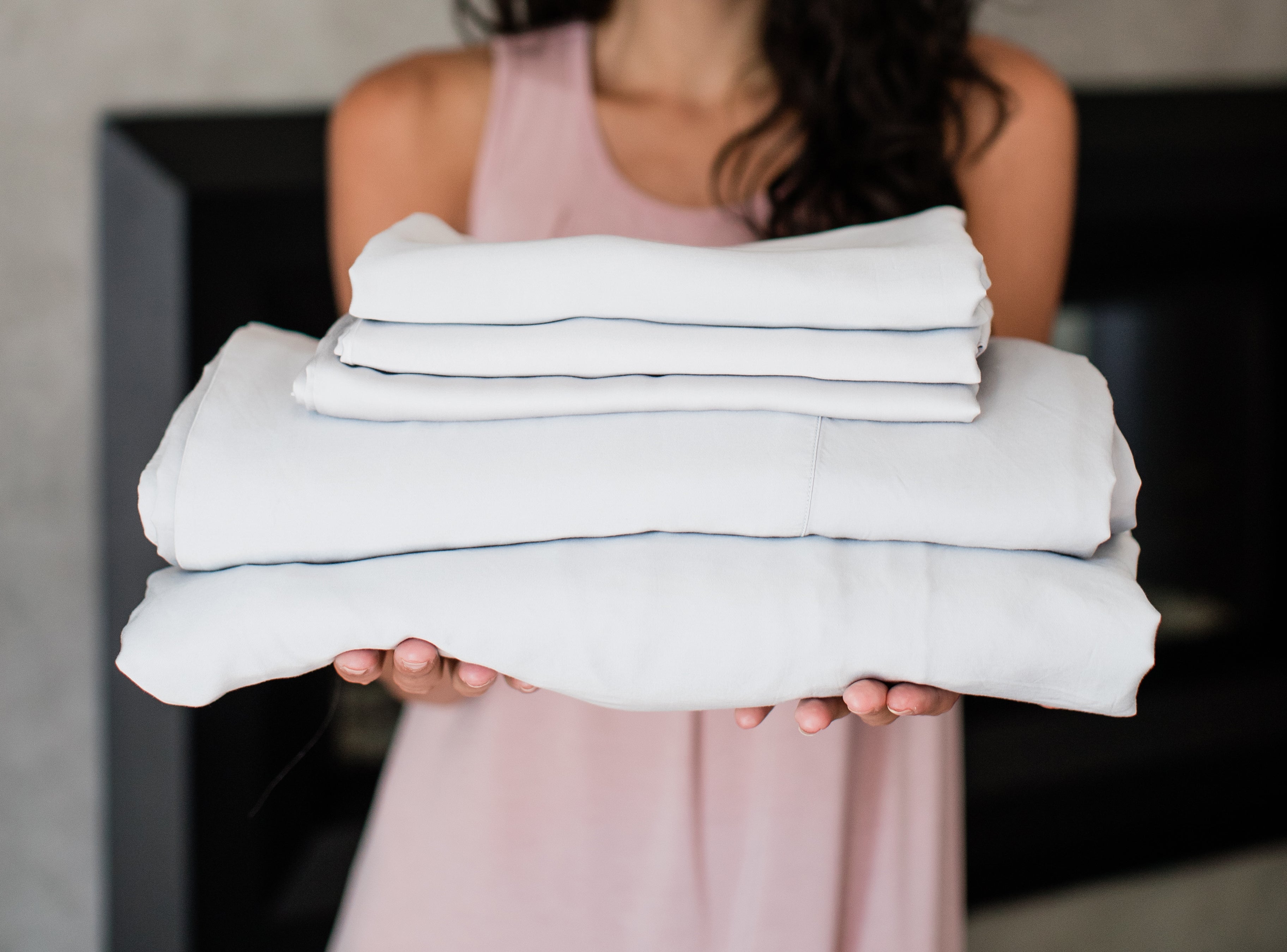 Woman holding a stack of soft YALA bamboo sheets.