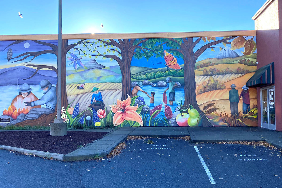 Mural of people in nature through the seasons on the Ashland Food Bank Building