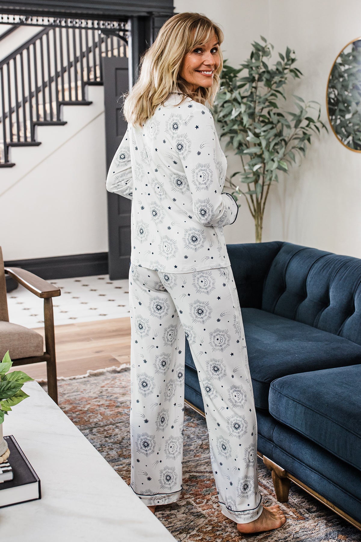 A woman standing and smiling while looking back over her shoulder, wearing Yala Aber Classic Button Front Pajama Set in Celestial Print