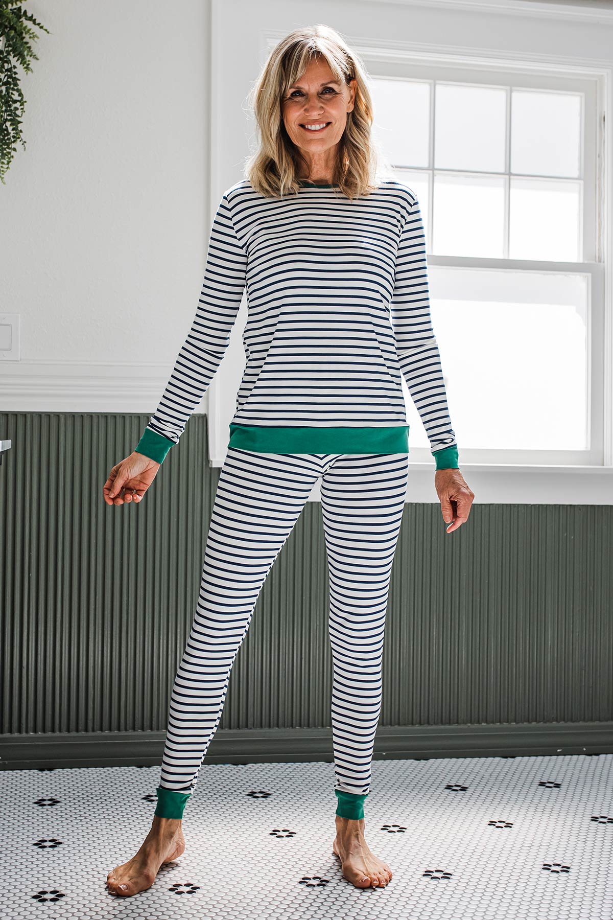 A woman standing and smiling with her hands at her sides, her stance wide, wearing Yala Lola Striped Bamboo Pajama Set in Navy Newport Stripe