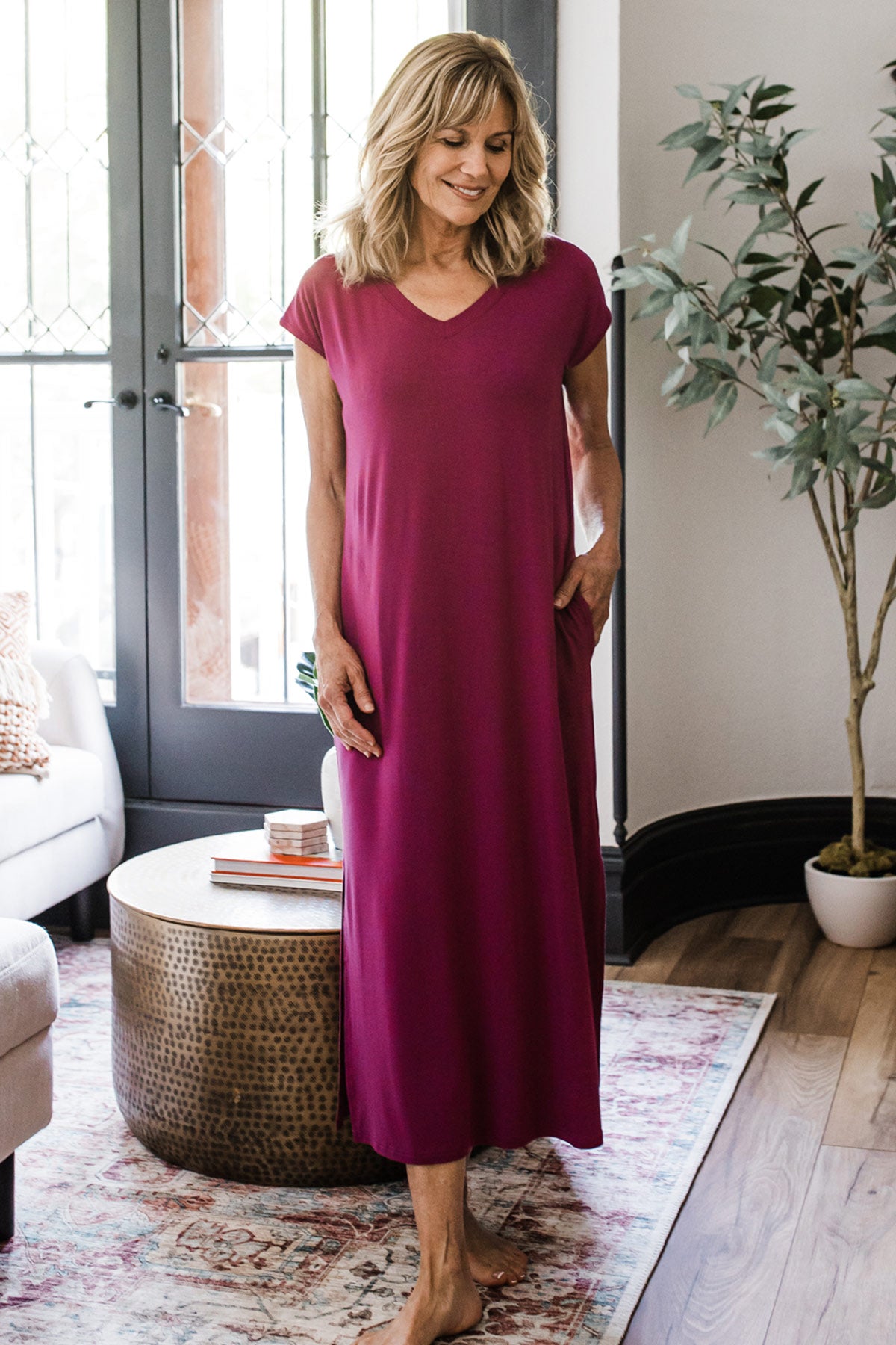 A woman standing and smiling with one hand in her pocket, wearing Yala Sloane V-Neck Cap Sleeve Bamboo Maxi Dress in Boysenberry