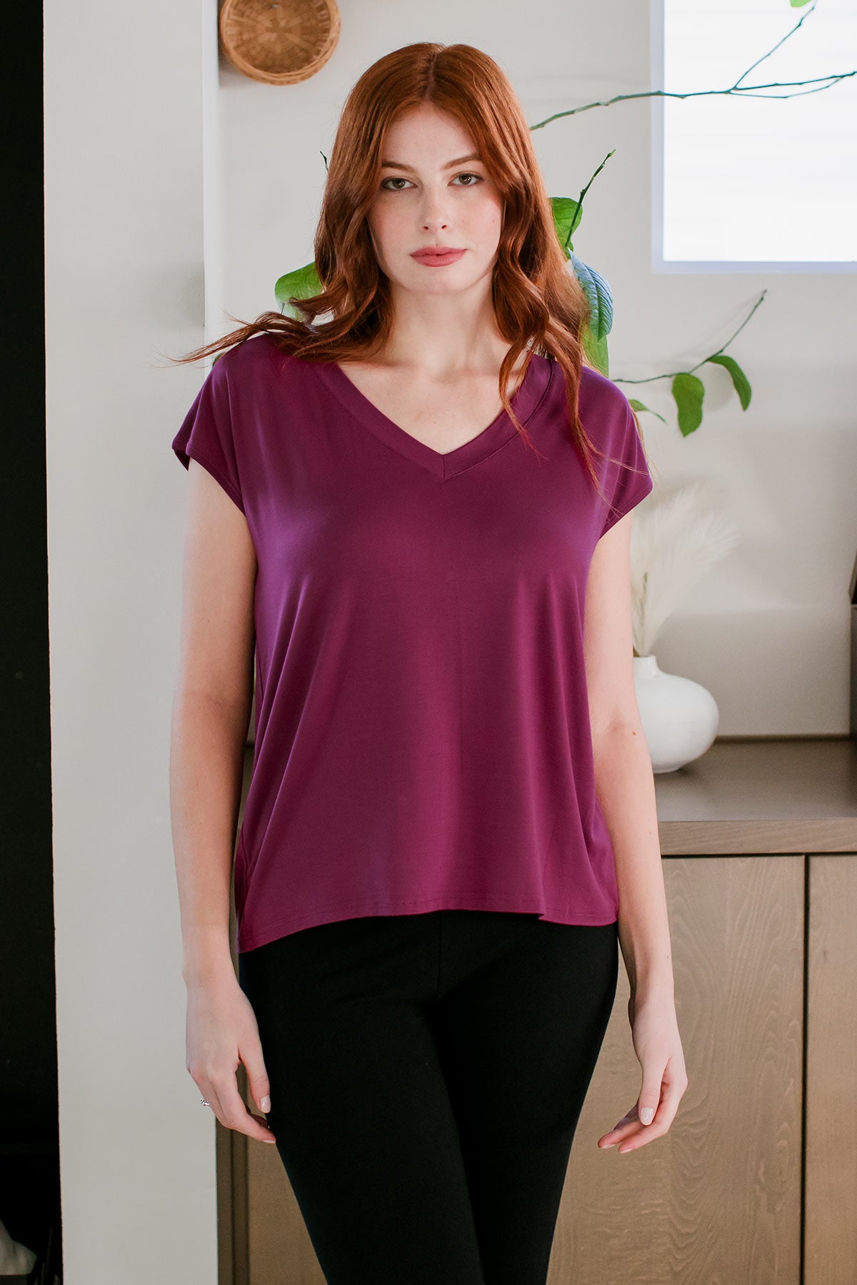 A woman standing with both hands at her sides, wearing Dakota V-Neck Cap Sleeve Bamboo Top in Boysenberry