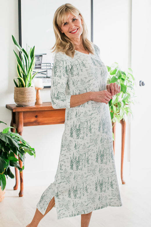 A woman standing facing to the side, one leg stretched behind her and hand held together at her waist, wearing Yala Haley Crossover Front 3/4 Sleeve Bamboo Nightgown in English Garden Print