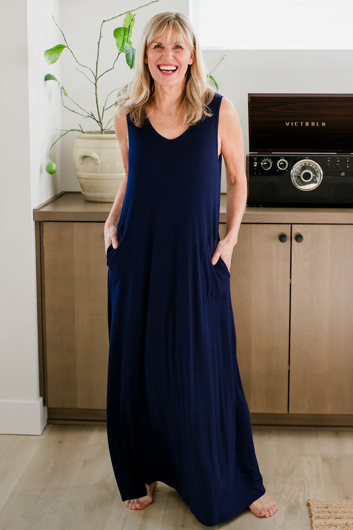 A woman standing with both hands in her pockets and a smile on her face, wearing Yala Kinsley Sleeveless Bamboo Maxi Dress in Navy