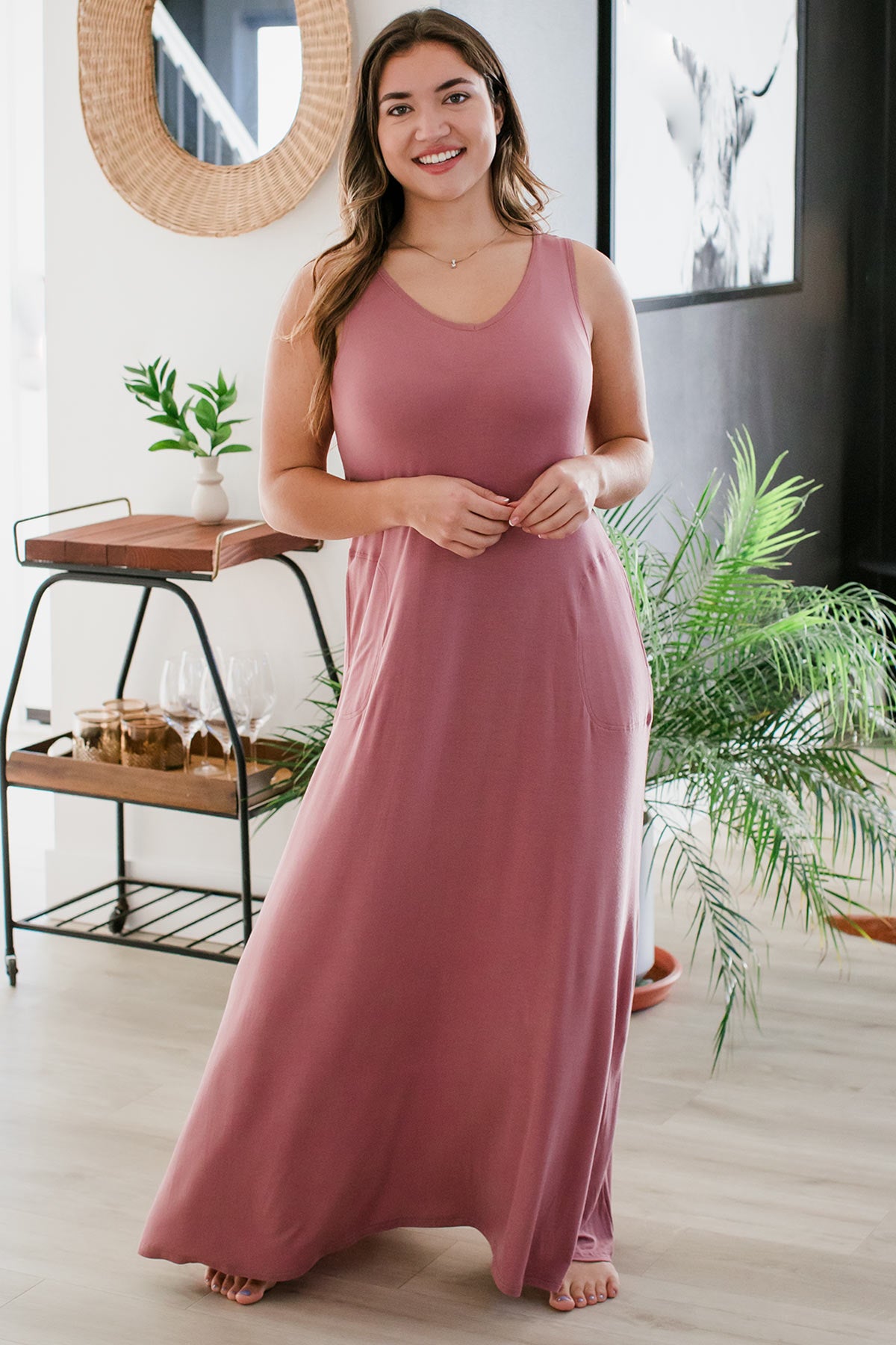 A woman standing with her hips tilted to the side and both her hands held together in front of her, wearing Yala Kinsley Sleeveless Bamboo Maxi Dress in Rose