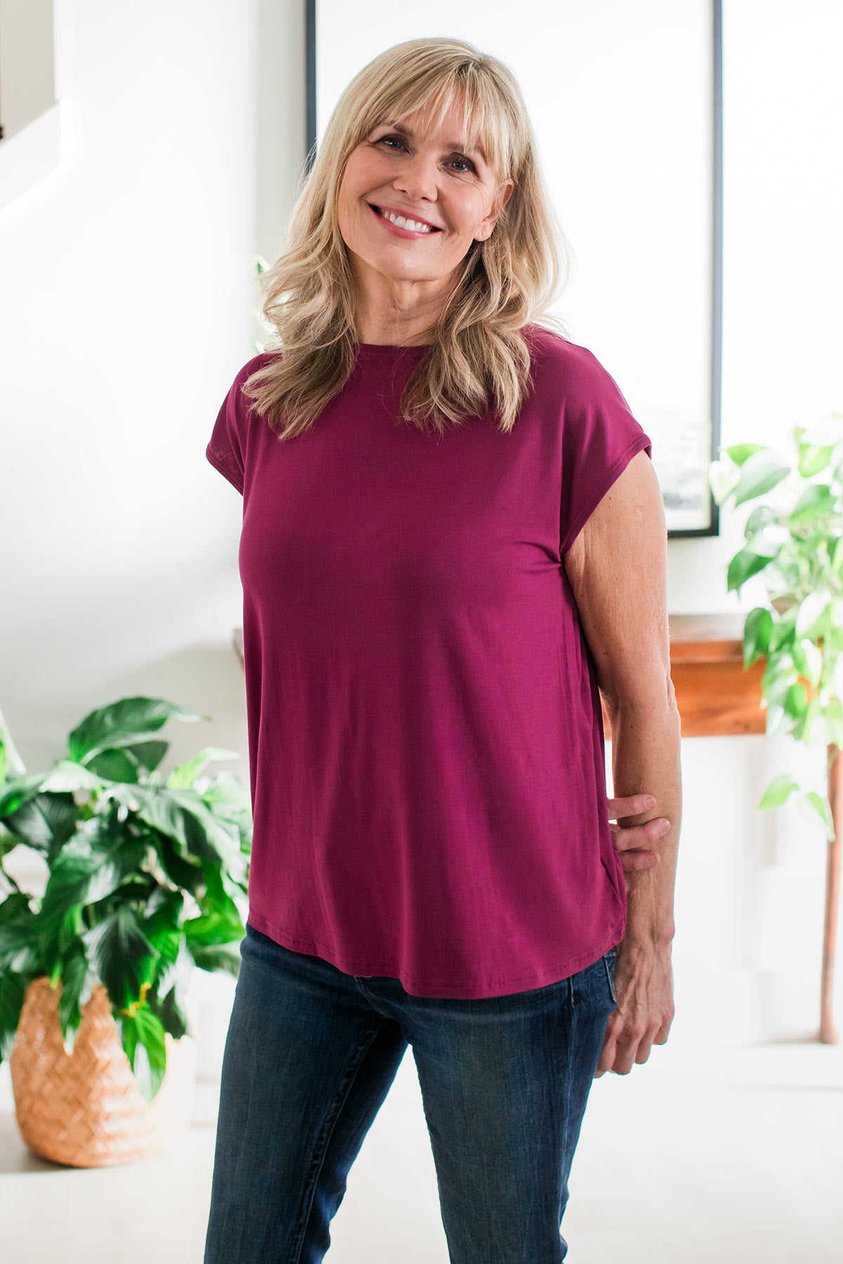 A woman standing with one arm at her side and the other arm crossed behind her back, wearing Yala Opal swing Bamboo Top in Boysenberry