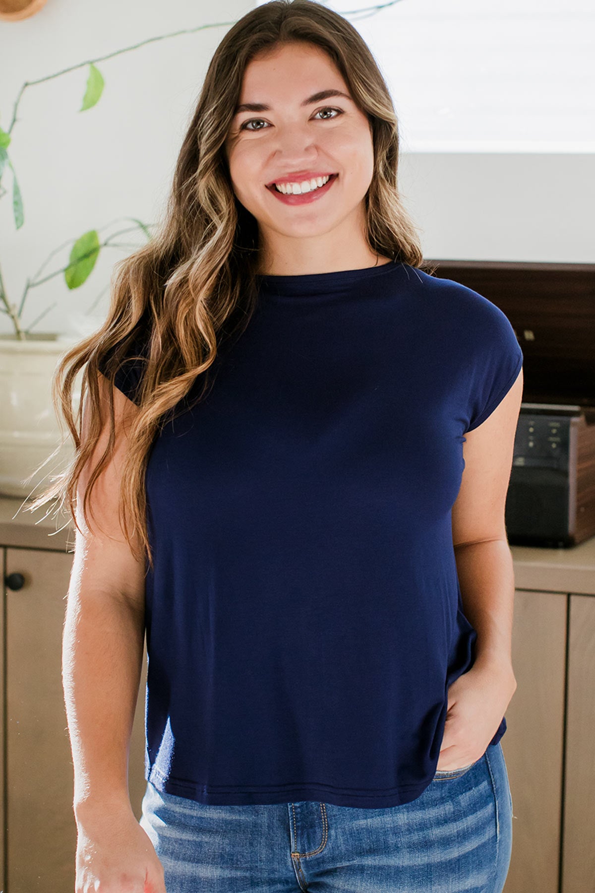 A woman standing with one hand in her pocket and a smile on her face, wearing Yala Opal Bamboo Swing Top in Navy
