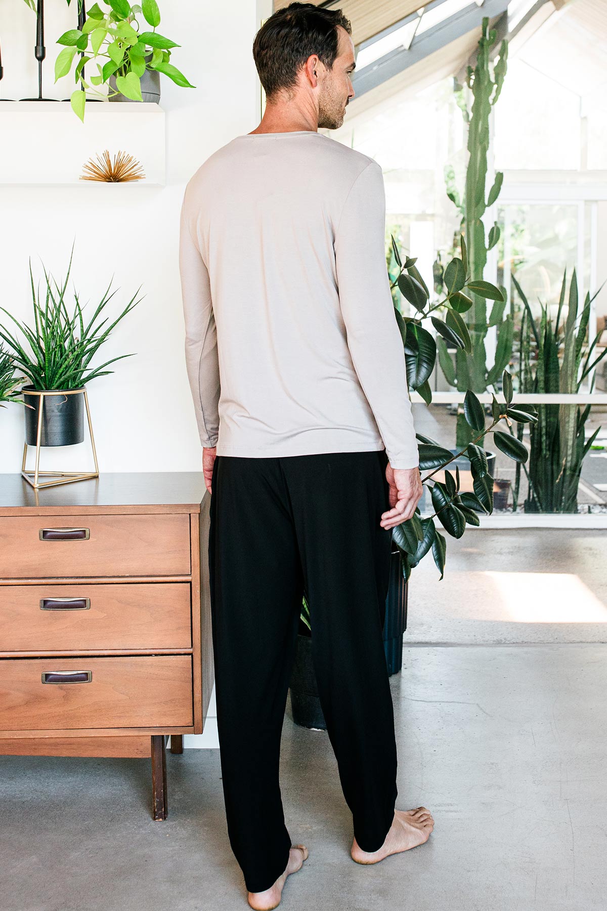 A man standing with his back towards the camera, wearing Yala Men's Hayden ButterSoft Bamboo Lounge Pants in Black