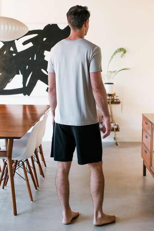 A man standing facing away from the camera with his hands at his sides, wearing Yala Men's Mateo ButterSoft Bamboo Lounge Shorts in Black