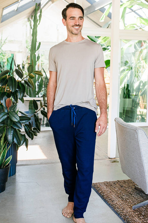 A man striding forward and smiling with one hand in his pocket, wearing Yala Men's Zach Bamboo & Organic Cotton Sweatshirt Jogger Lounge Pant in Navy