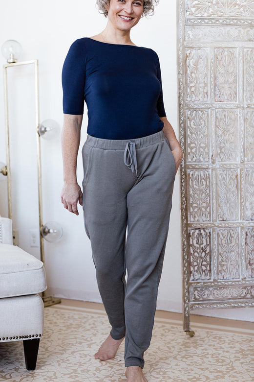 A woman standing and smiling with one foot forward and one hand in her pocket, wearing Yala Angel Bamboo and Organic Cotton Jogger Sweatshirt Lounge Pants in Space Grey