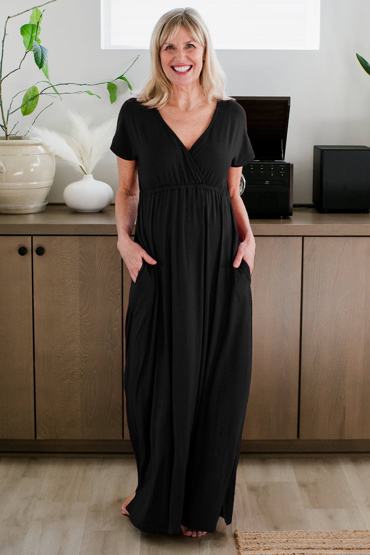 a woman standing and smiling with both hands in her pockets, wearing Zoey Crossover Bamboo Maxi Dress in Black