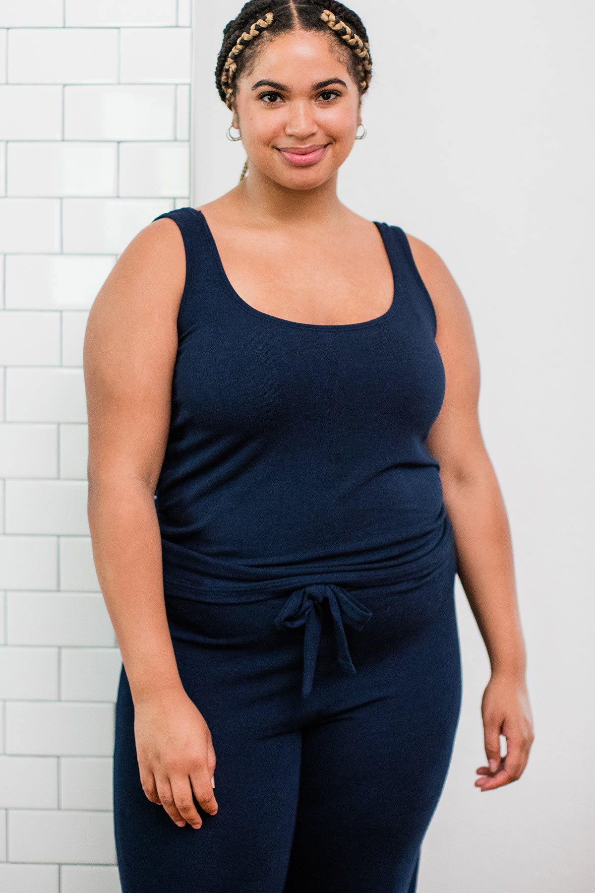 A woman standing and smiling with both hands at her sides, wearing Yala Claire Bamboo Sweater Tank Top in Navy