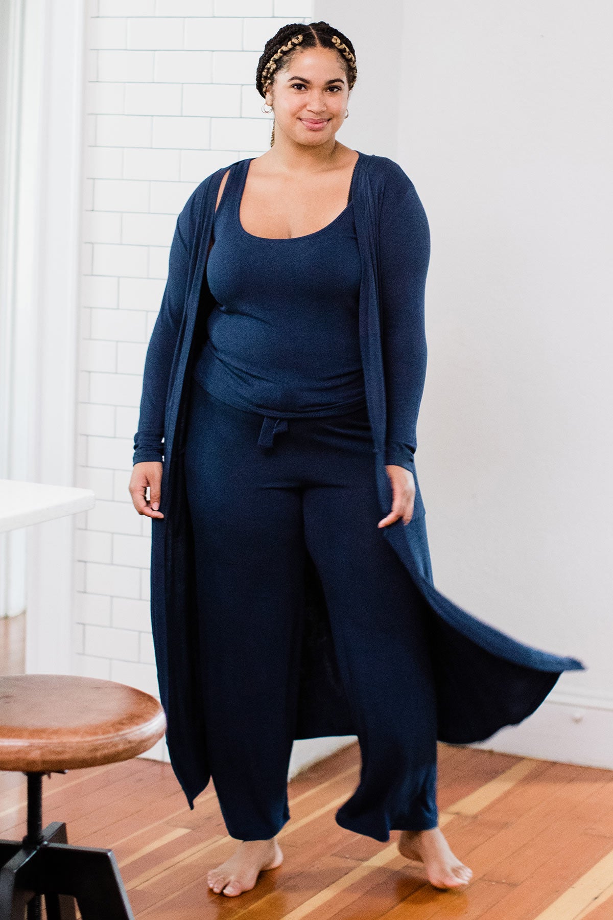 A woman standing and smiling with both hands at her sides, wearing Yala Claire Bamboo Sweater Tank Top in Navy