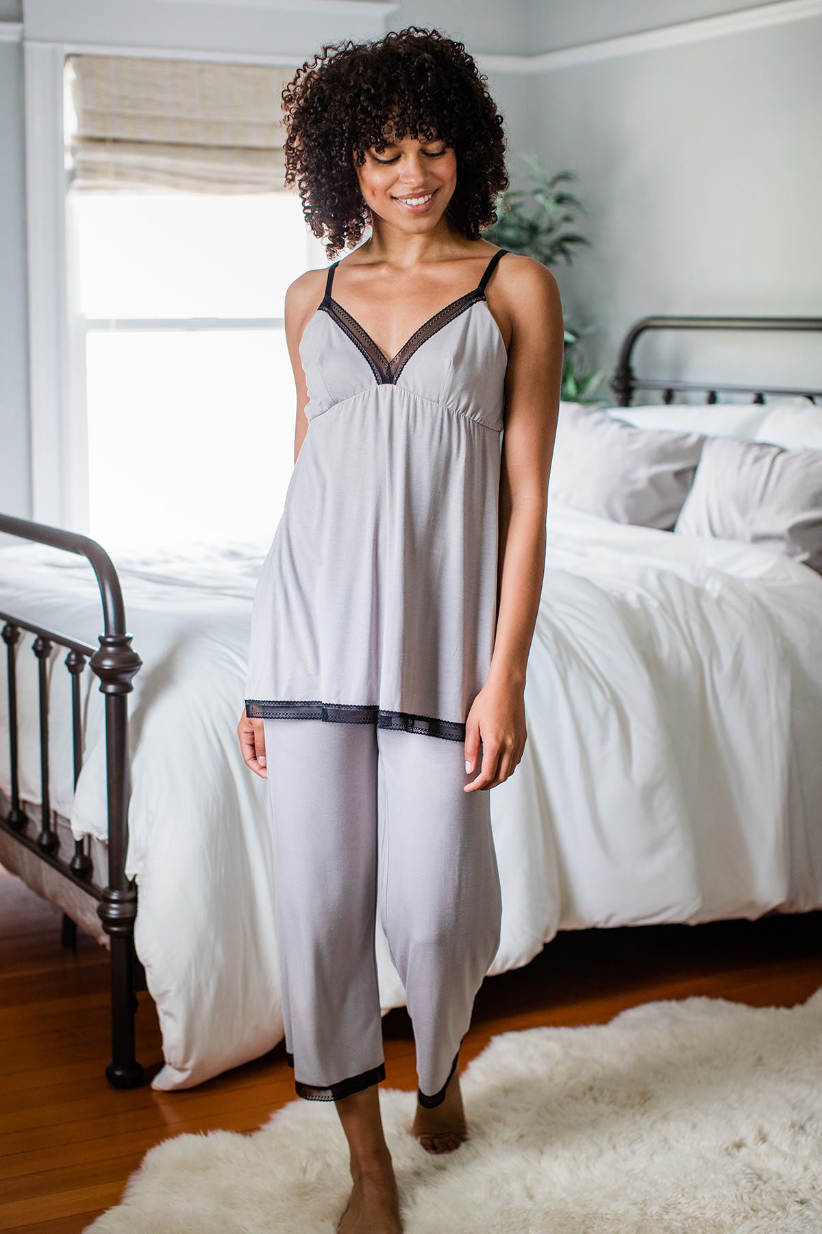A woman walking forward and smiling while looking downward, wearing Yala Iris Bamboo Lace Pajama Set in Ash
