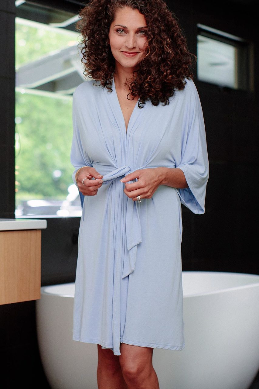 A woman standing and smiling with both hands on her robe's belt, wearing Yala Nina Elbow Sleeve Belted Bamboo Robe in Sky