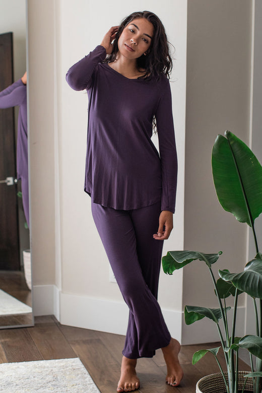 A woman standing with one leg crossed in front of the other and one hand in her hair, wearing Yala Norah Long Sleeve Bamboo Pajama Set in Aster