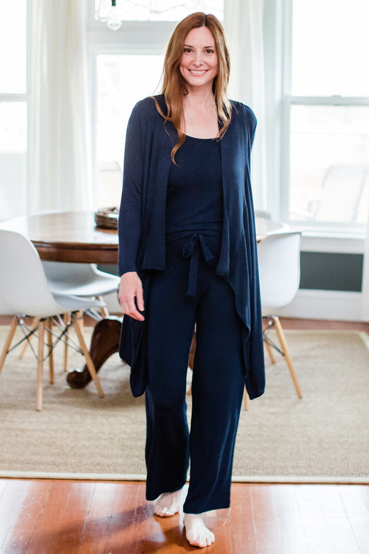 A woman standing and smiling with one foot forward, wearing Yala Peyton Bamboo Sweater Drawstring Lounge Pants in Navy