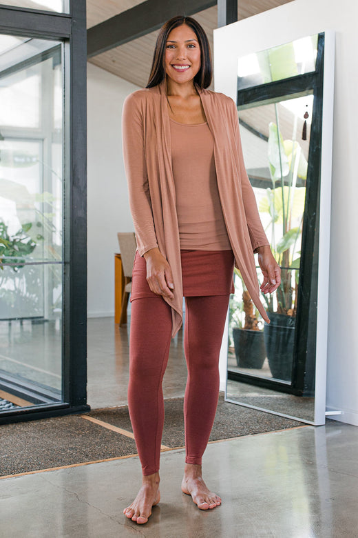 A woman standing and smiling, wearing Yala Taylor Ultra-Stretch Bamboo and Organic Cotton Skirt Leggings in Amber