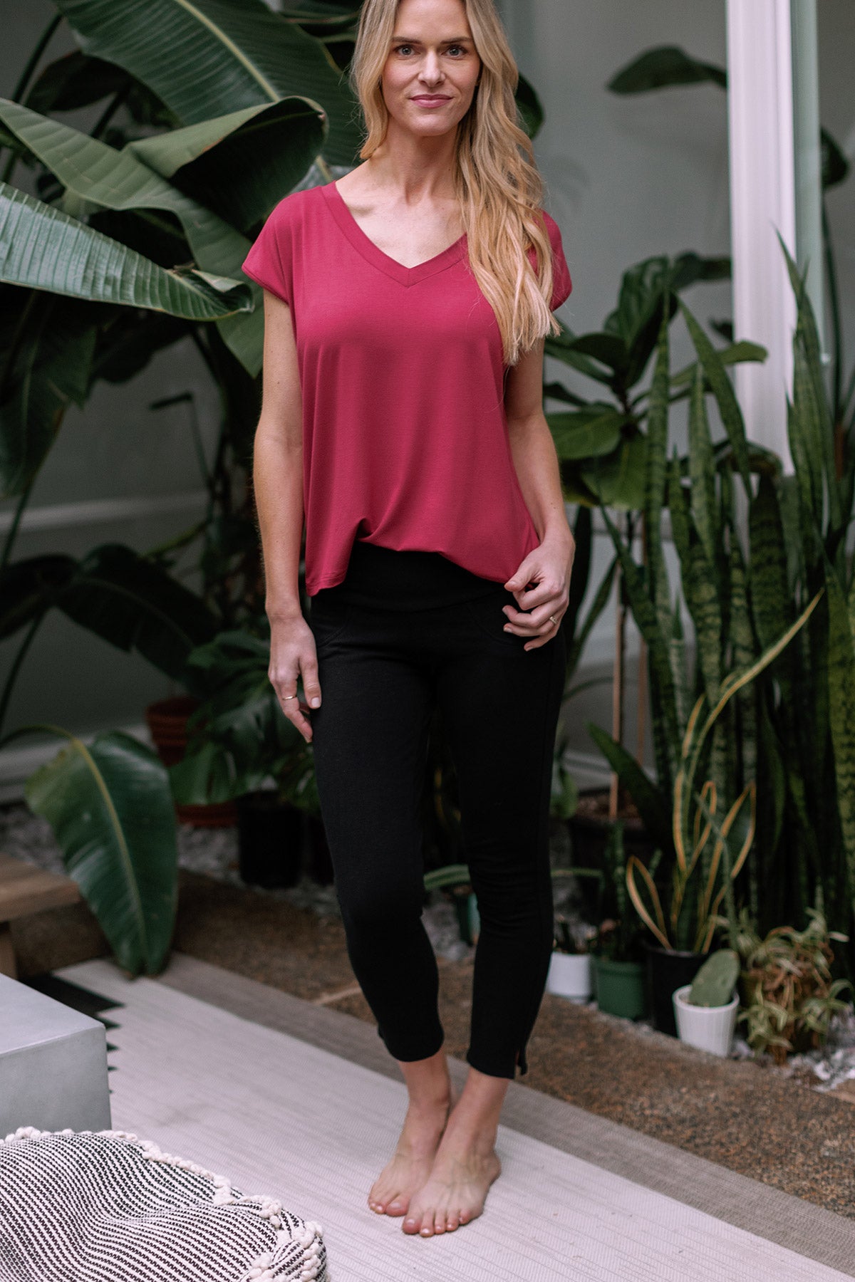 A woman standing with one hand on her hip ,wearing Yala Abby Mid-Waist Cropped Bamboo and Organic Cotton Pencil Pants in Black