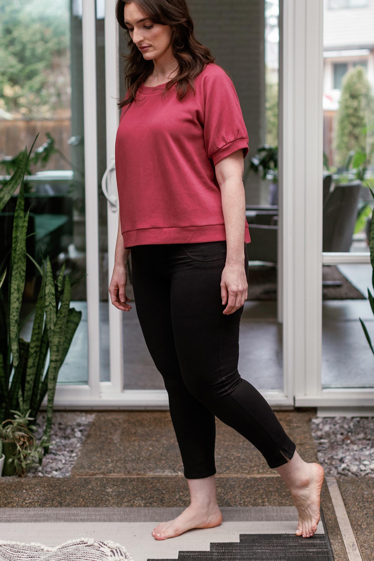 A woman striding across frame and looking downwards, wearing Yala Abby Mid-Waist Cropped Bamboo and Organic Cotton Pencil Pants in Black