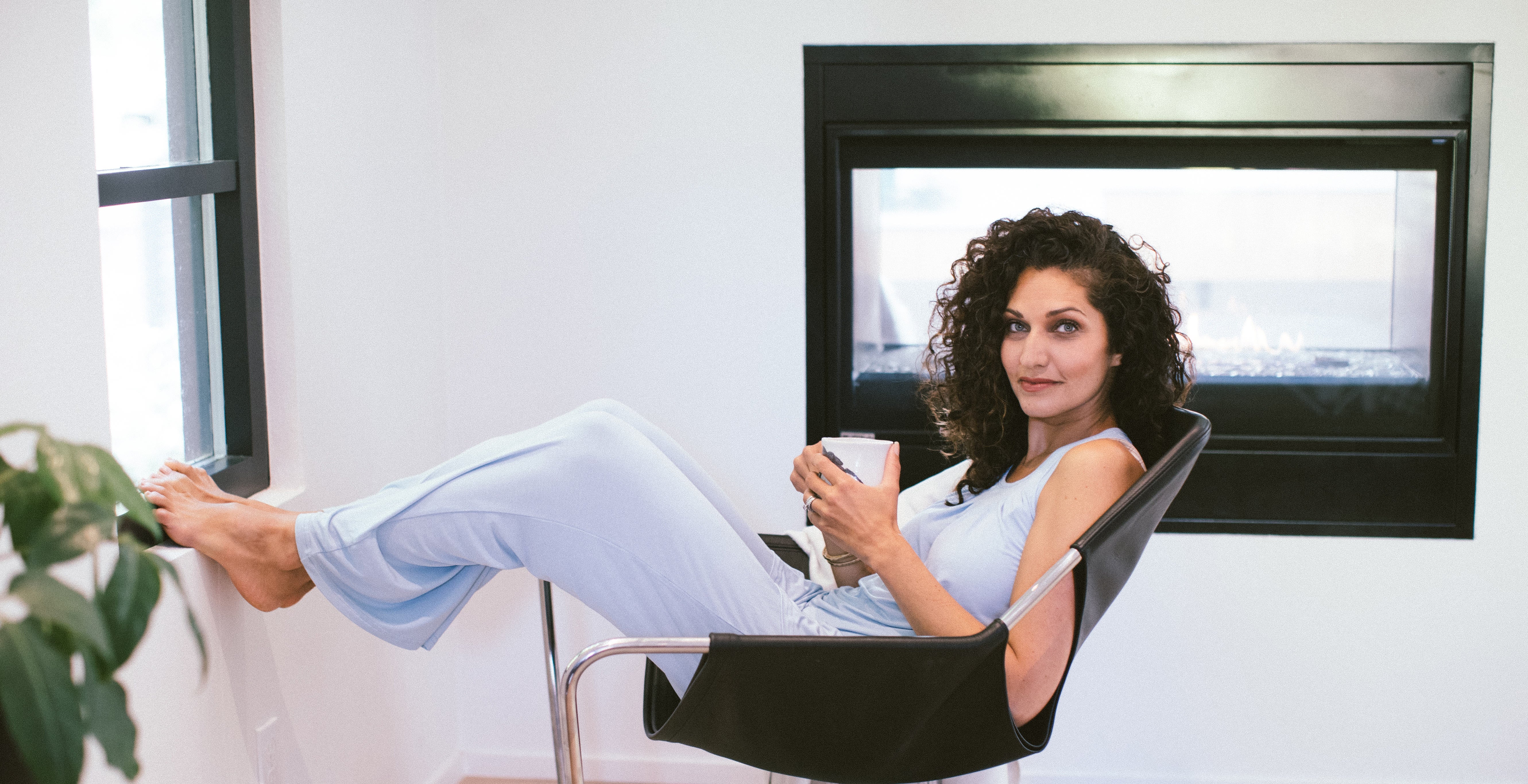 Woman relaxing by a window, wearing a Delia Pajama Set.