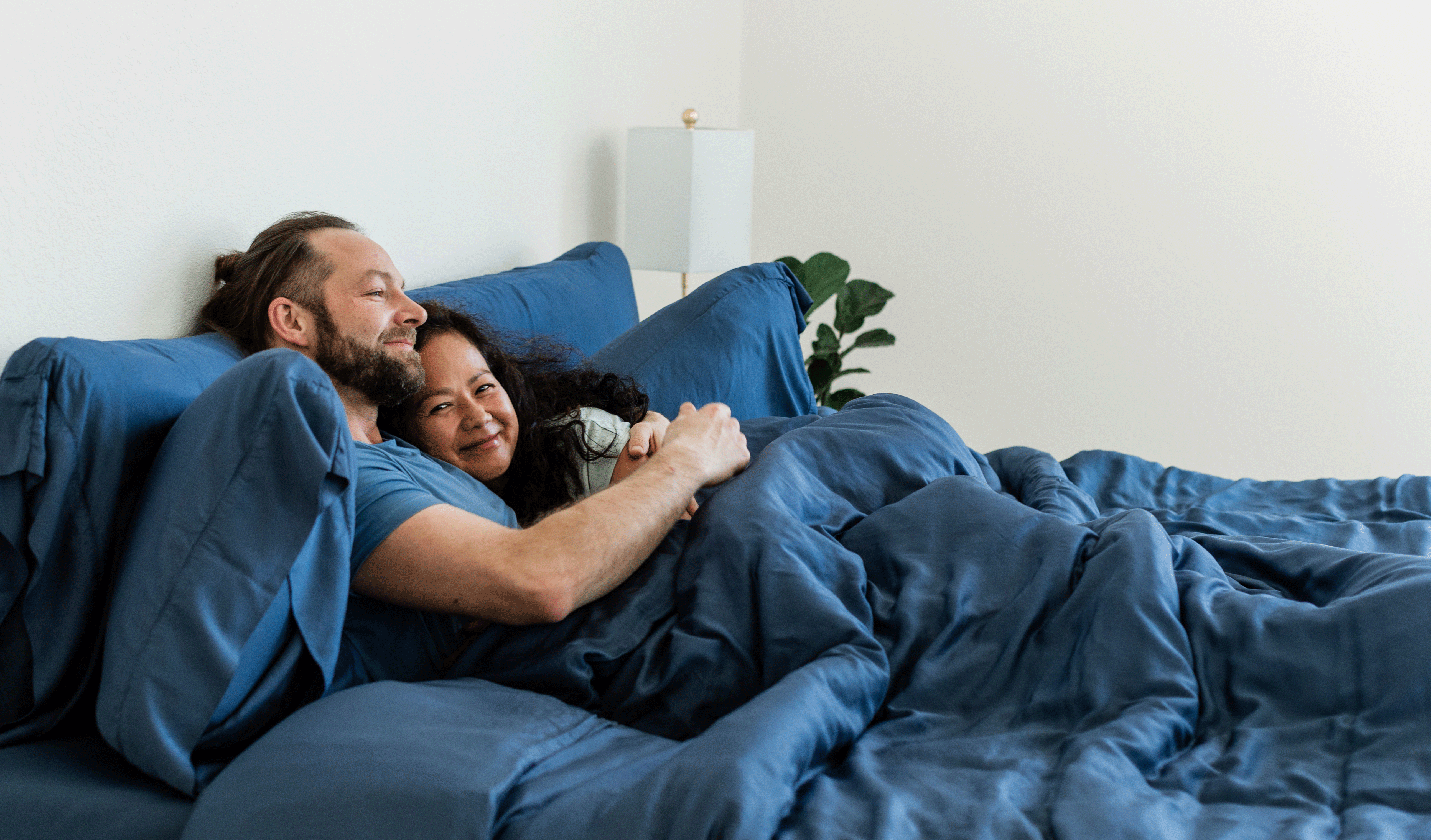 Happy couple snuggling in a cozy bed.