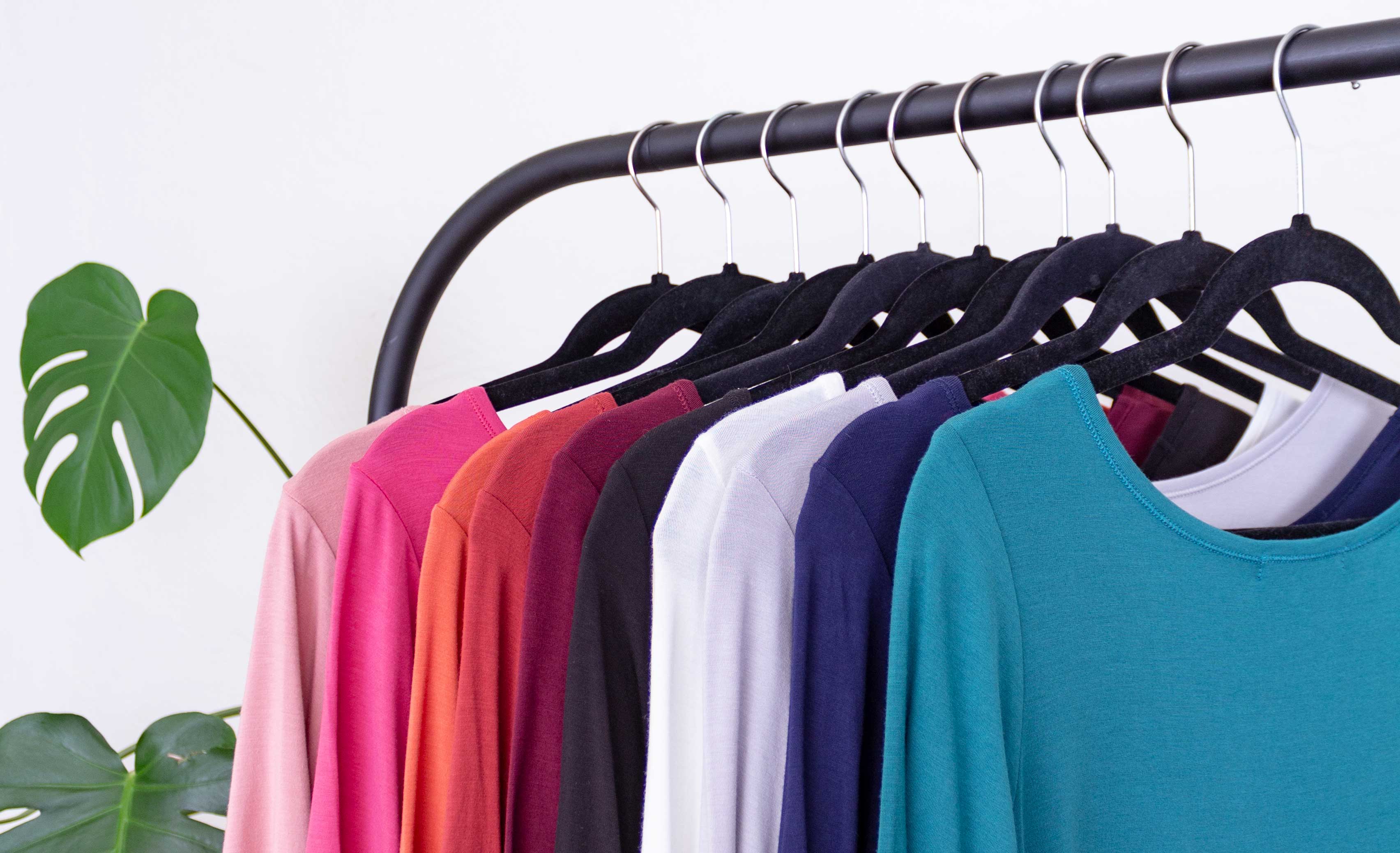Several brightly colored YALA shirts hanging on a clothing rack.