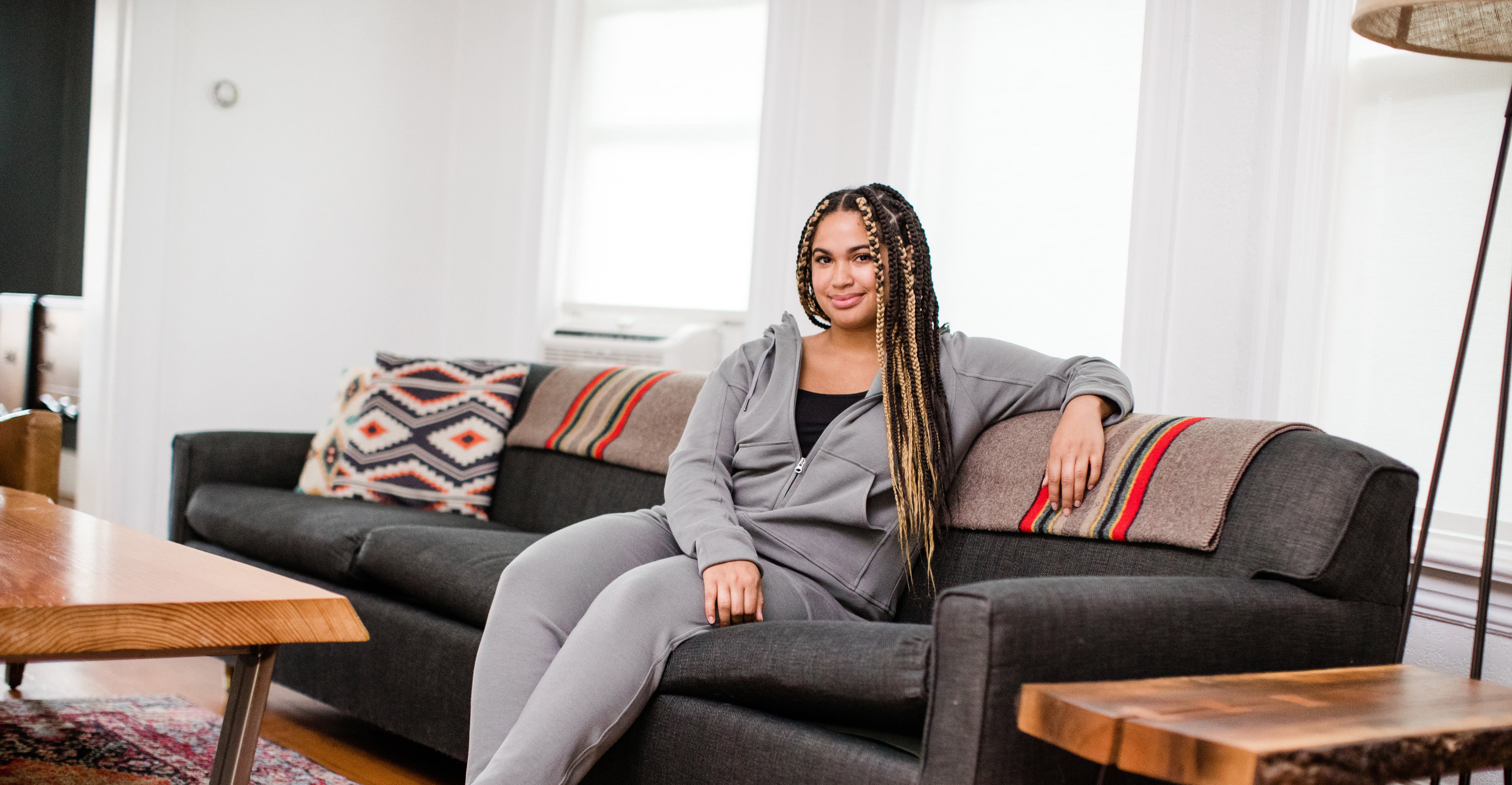 Woman reclined on a couch wearing YALA hoodie and joggers