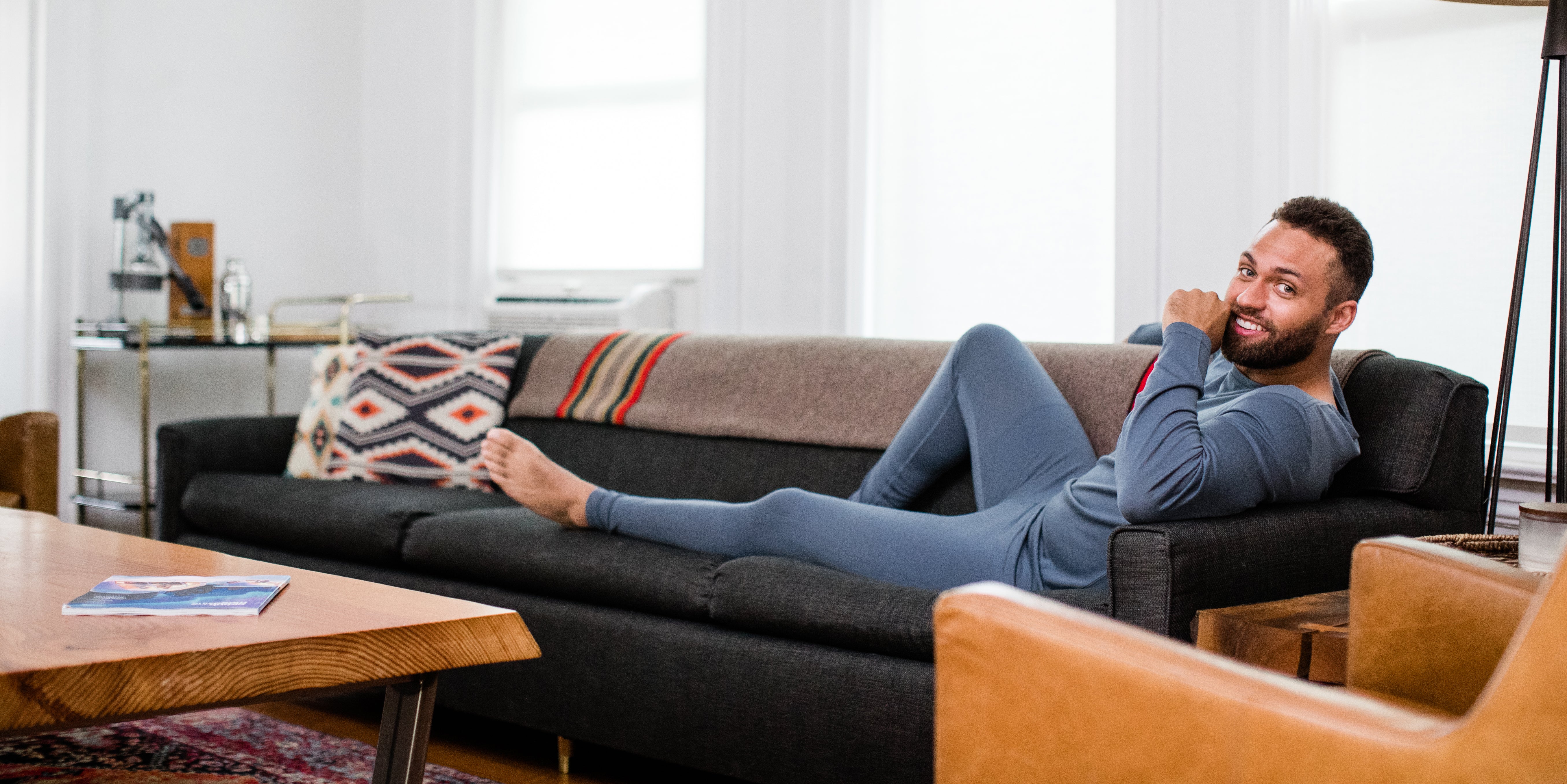 Man lounging on a couch in YALA's soft merino wool shirt and leggings