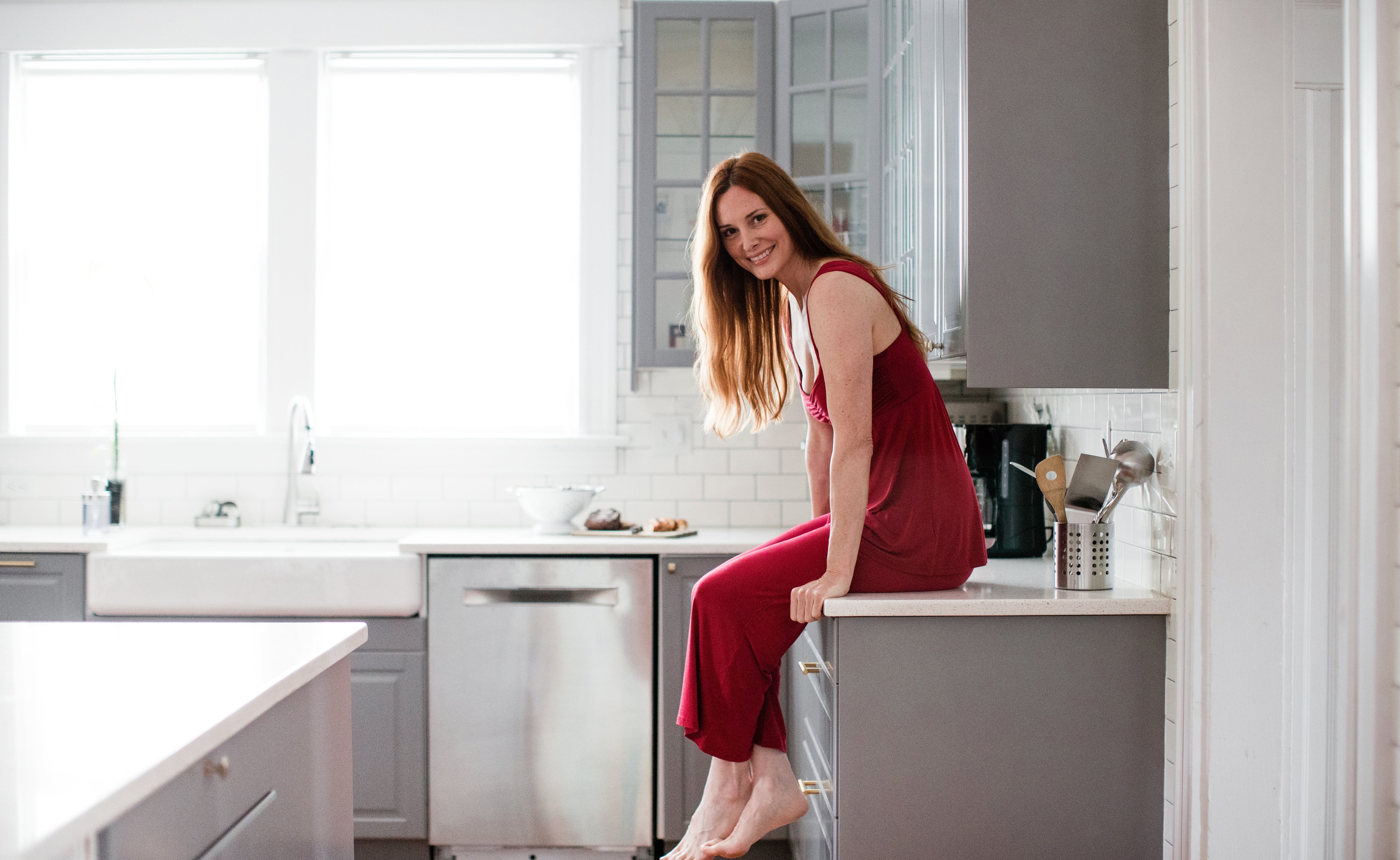 Woman sitting on a kitchen counter in red YALA Cleo Pajamas.