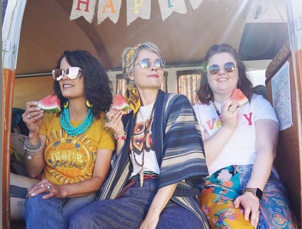 Three women eating watermelon out of a Volkswagen Bus