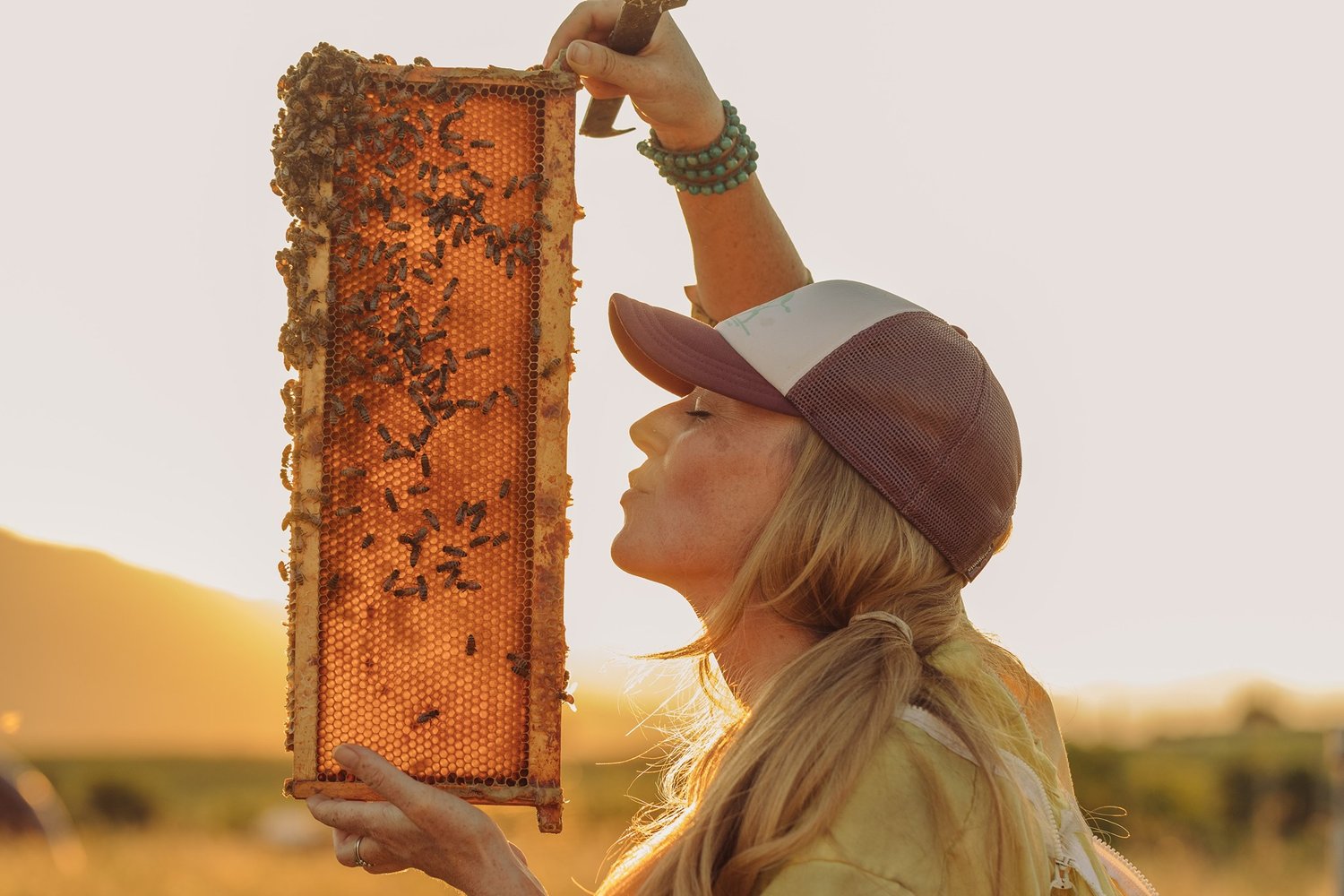 A Female bee keeper blows a kiss at a honeycomb full of bees