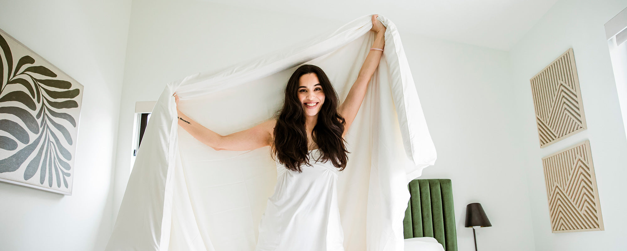 woman on her knees in bed with soft silk-filled comforter and luxury bamboo pajamas.