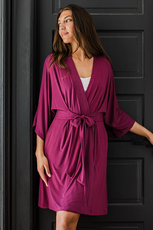 A womand leaning back against a closed door while looking off to the side, wearing Yala Nina Elbow Sleeve Belted Bamboo Robe in Boysenberry