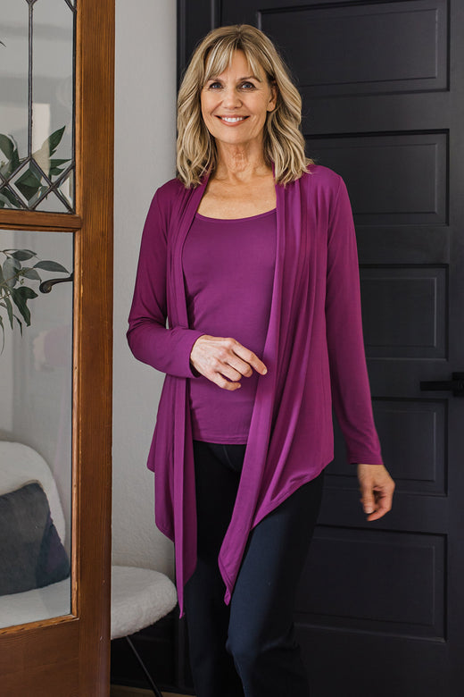A woman walking towards the camera and smiling, wearing Yala Sophie Bamboo Cardigan Wrap in Boysenberry