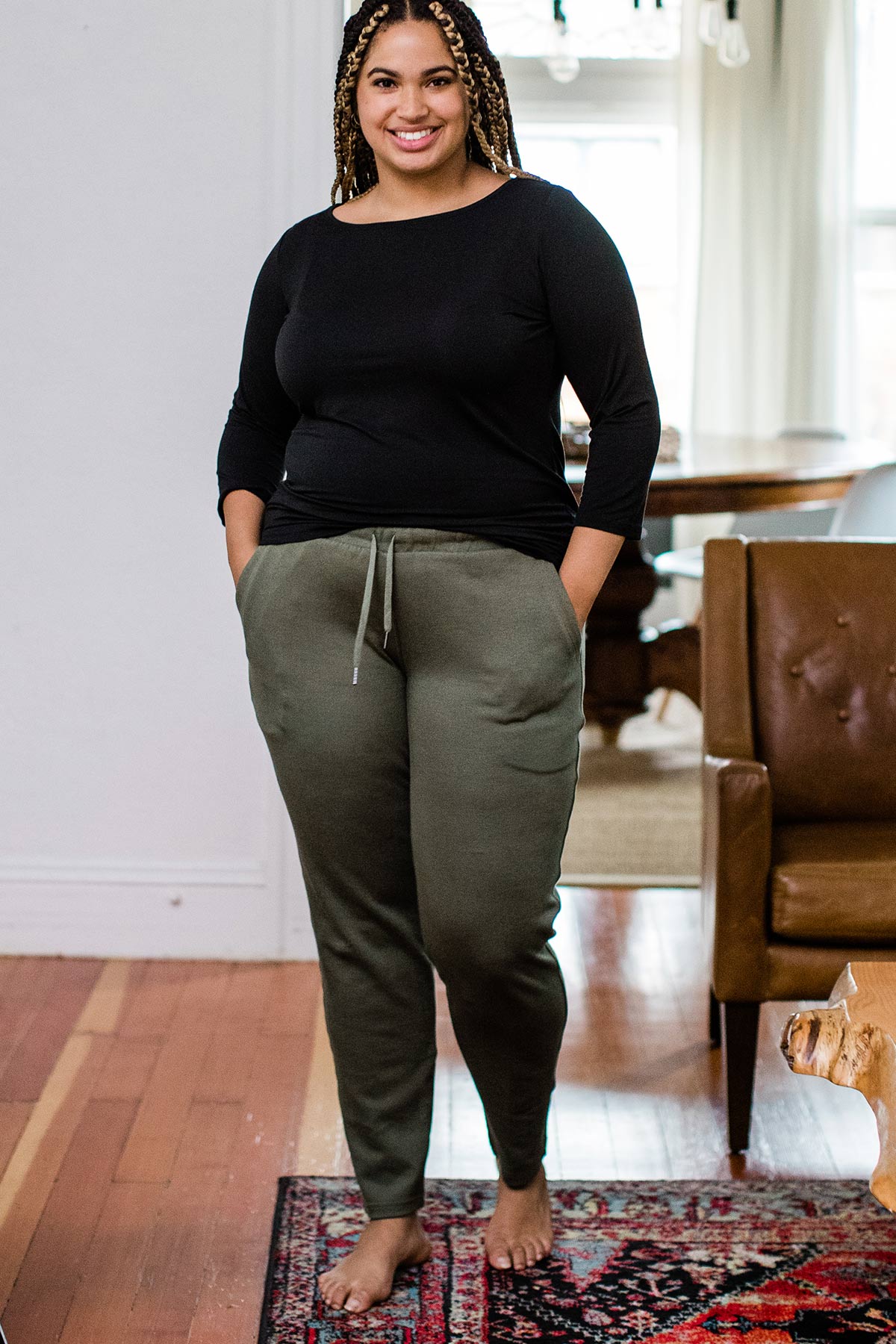 A woman standing and smiling with both hands in her pockets, wearing Yala Angel Bamboo and Organic Cotton Jogger Sweatshirt Lounge Pants in Moss