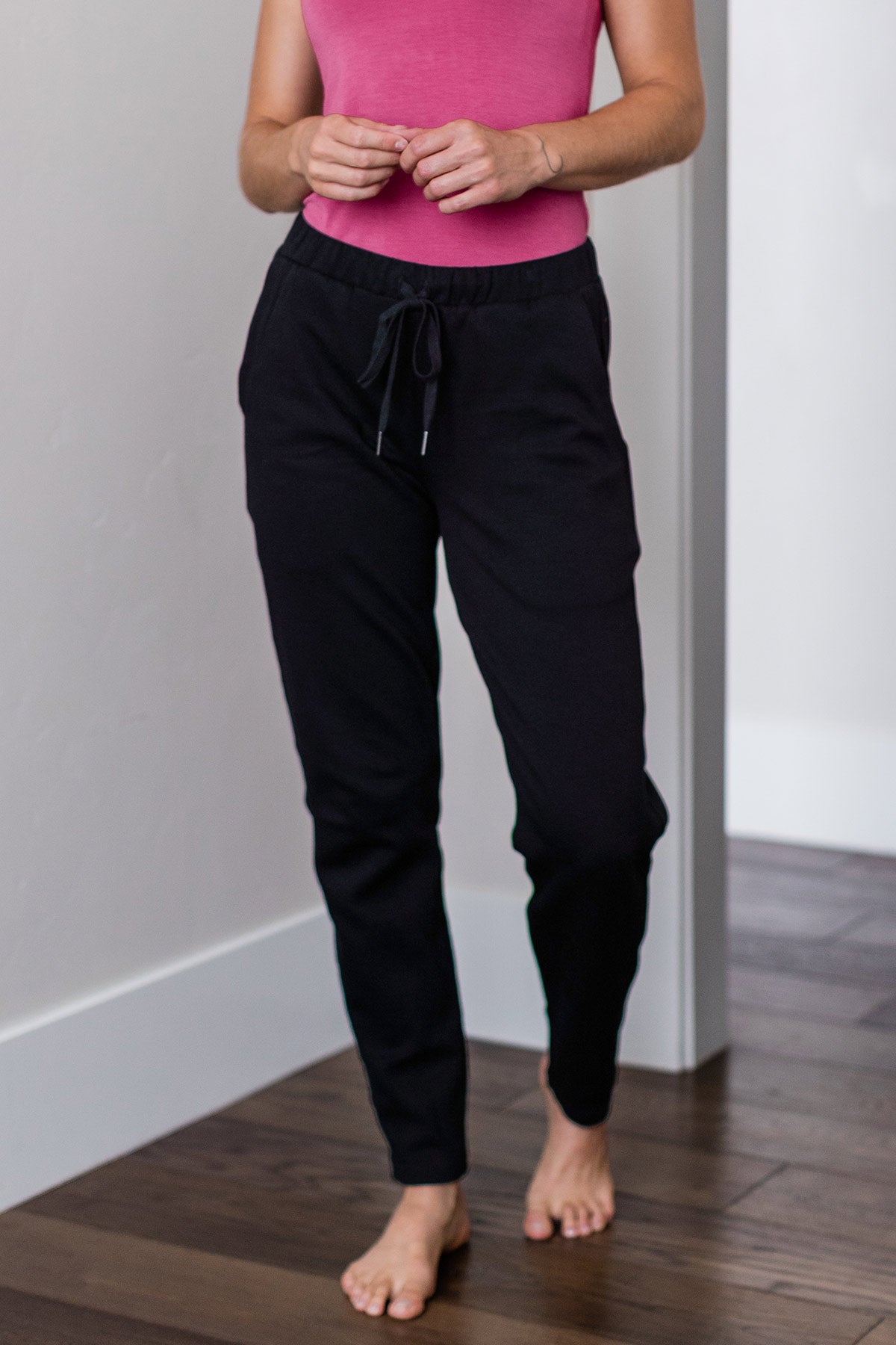 Cropped shot of a woman's waist and legs with her hands held in front of her, wearing Yala Angel Bamboo and Organic Cotton Sweatshirt Jogger Lounge Pants in Black