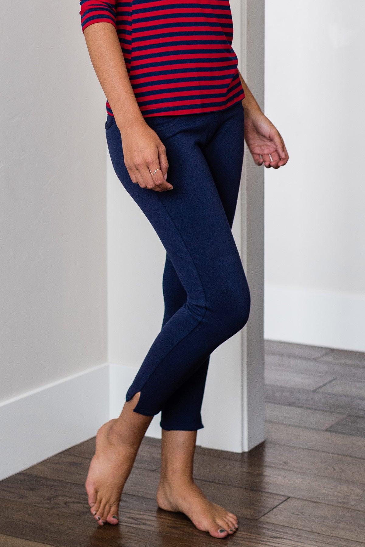 Cropped shot of a woman's waist and legs standing with one knee bent, wearing Yala Audrey Cropped Bamboo and Organic Cotton Pencil Pants in Navy