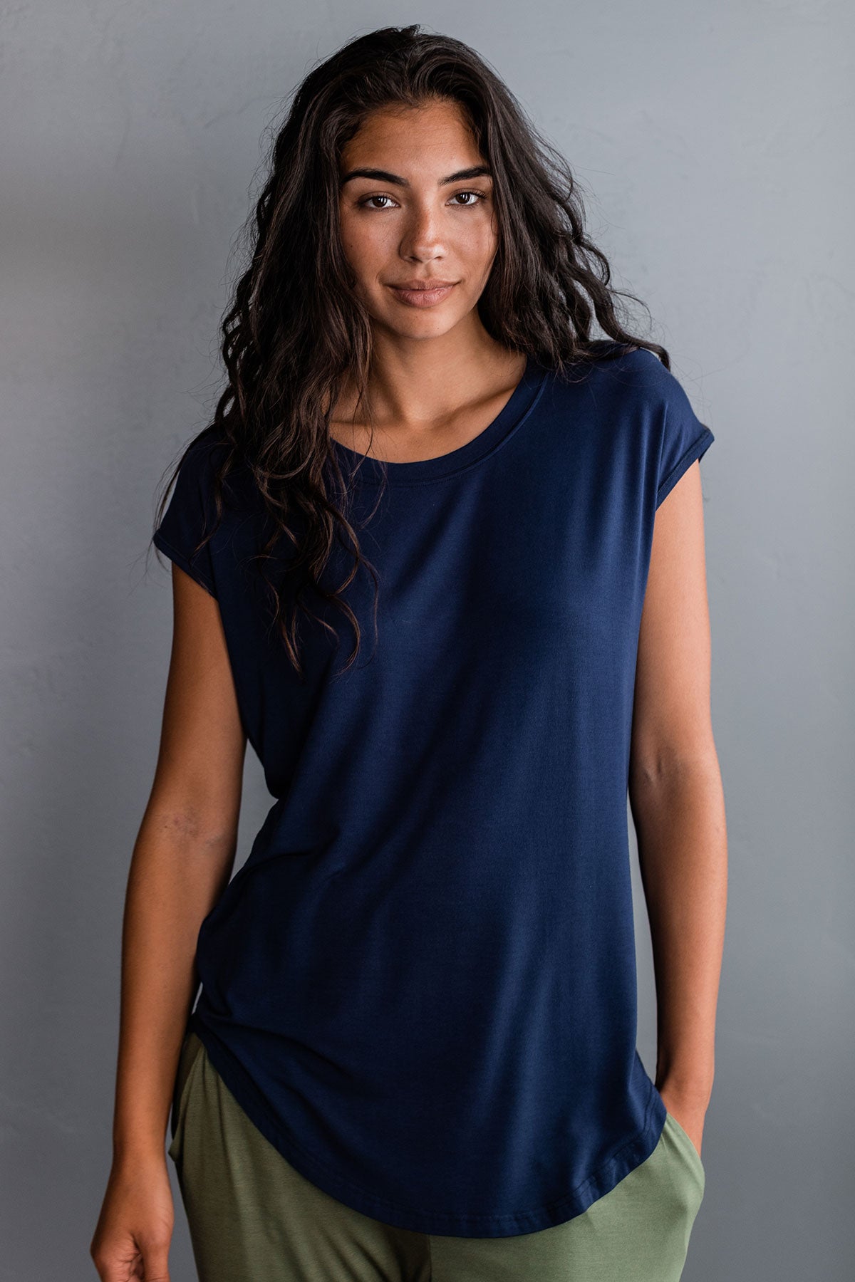A woman standing with one hand in her pocket, wearing Yala Cassidy Cap Sleeve Bamboo Boyfriend Tunic in Navy