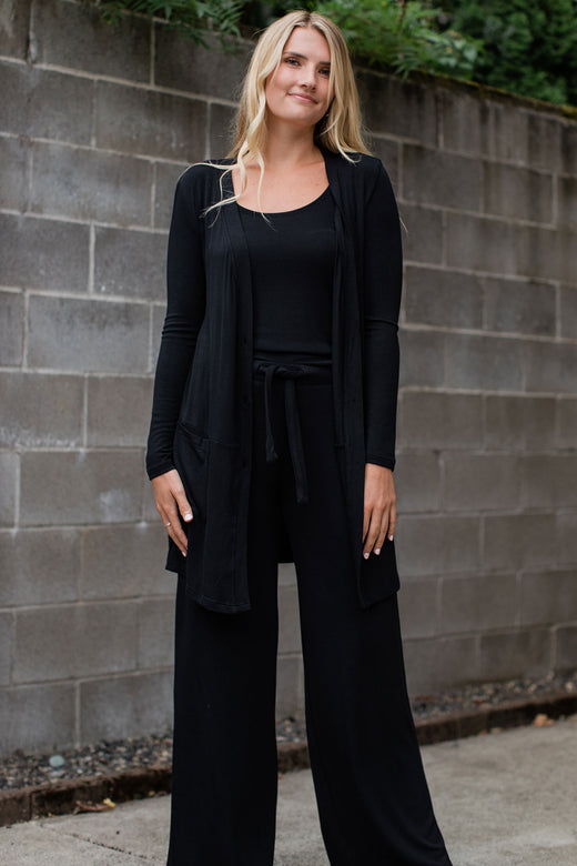 A woman standing with both hands at her sides, wearing Yala Claire Bamboo Sweater Tank Top in Black