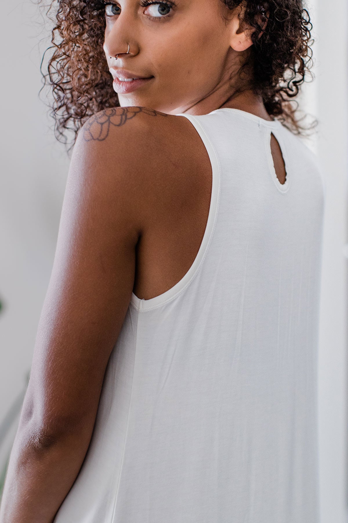 Close shot of a woman's back with her looking back over her shoulder, wearing Yala Delia Gathered Tank Bamboo Nightgown in Natural