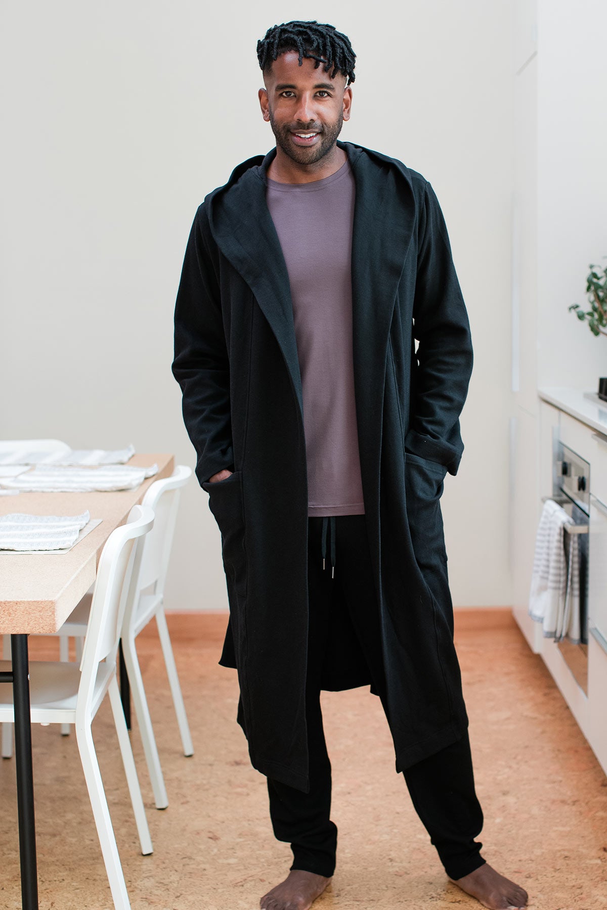 A man standing and smiling with his hands in his pockets, wearing Yala Elliot Bamboo and Organic Cotton Sweatshirt Hooded Robe in Black