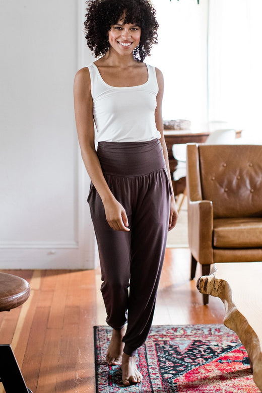 A woman standing and smiling while walking forwards, wearing Yala Geena Lightweight Bamboo Jogger Lounge Pants in Mink