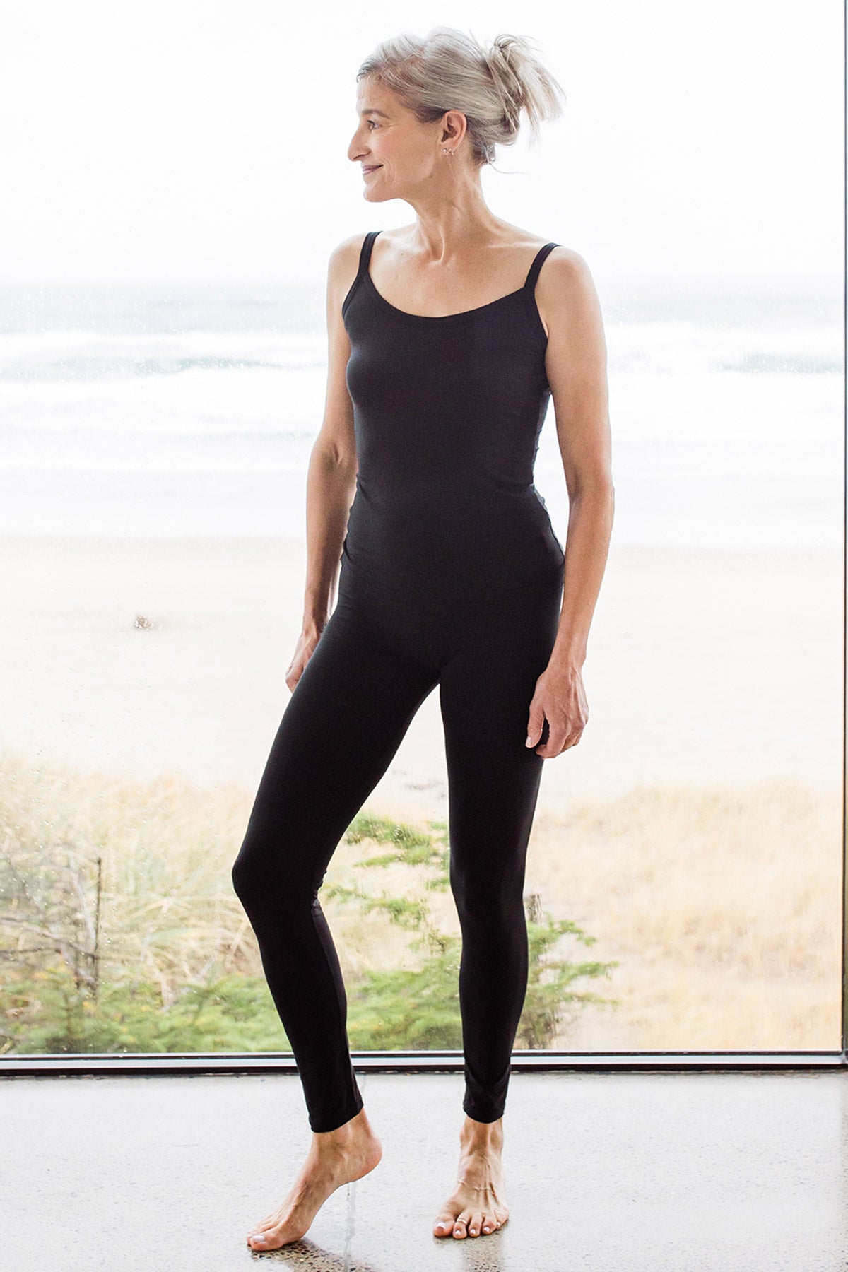 Woman standing and facing slightly to the side, wearingYala Grace Buttersoft™ Bamboo Full Length Leggings in Black