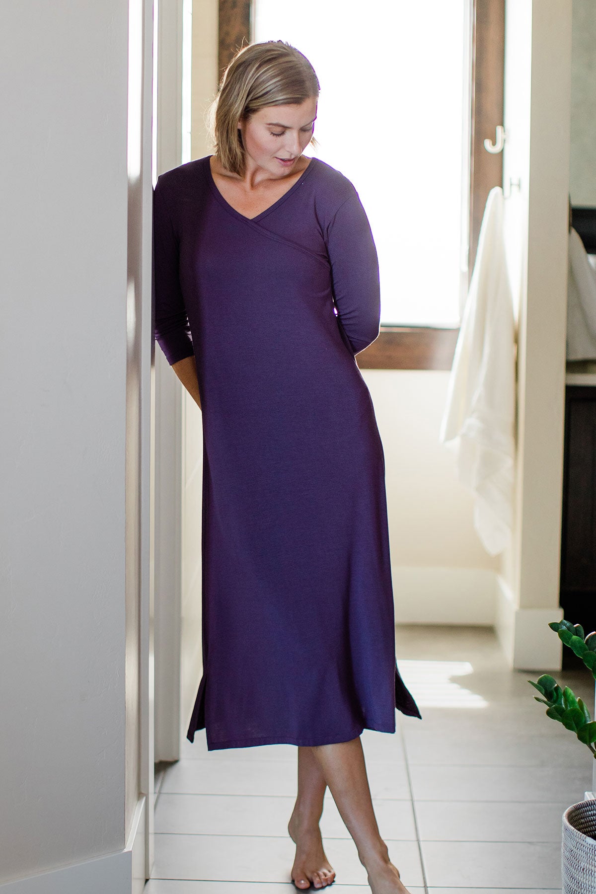 A woman standing with one leg in front of the other while leaning her shoulder against a wall, wearing Yala Haley Crossover Front Three Quarter Sleeve Bamboo Nightgown in Aster