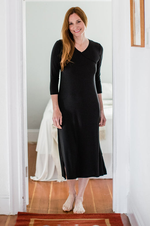 A woman standing and smiling with both hands at her sides, wearing Yala Haley Crossover Front Three Quarter Sleeve Bamboo Nightgown in Black