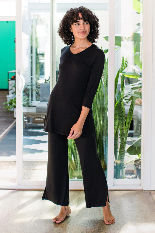 Woman standing and looking to the side while smiling, wearing Yala Haley Crossover Front 3/4 Sleeve Pajama Set in Black