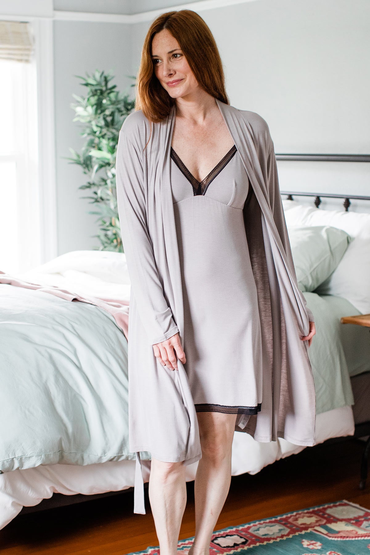 A woman standing and smiling while looking to the side, wearing Yala Iris Lace Bamboo Nightgown in Ash