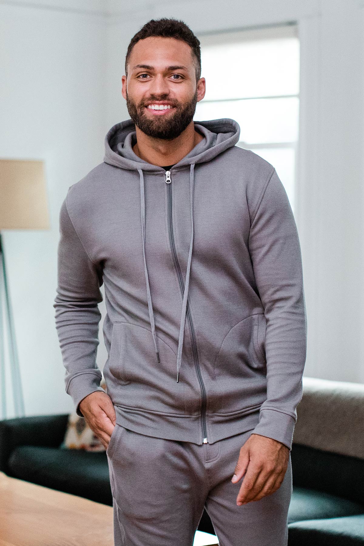 A man stnding and smiling with one hand in his pants pocket, wearing Yala Joey Men's Zip-Up Bamboo and Organic Cotton Sweatshirt Hooded Jacket in Space Grey